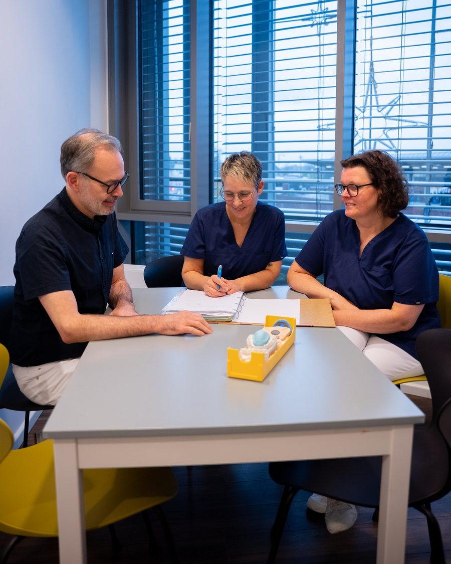 Dr. Vogel und zwei Kolleginnen am Tisch bei einer Teambesprechung